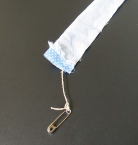 Safety pin threaded through material